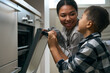 © Viacheslav Yakobchuk - Beautiful elegant female is looking to the son near the oven in the cuisine