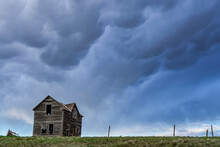 Old Farmstead On The Prairies Under A Stormy Sky; Saskatchewan, Canada