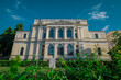 Front facade of national museum of bosnia and herzegovina on a summer day hiding behind some greenery.
