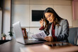 © Drazen - Asian businesswoman examining paperwork while working in office.