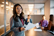 © Drazen - Happy Asian executive manager analyzing business reports with her team in office and looking at camera.