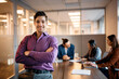 © Drazen - Confident Hispanic gay businessman with crossed arms in office looking at camera.