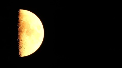 Wall Mural - Timelapse. A glowing golden huge moon as seen from earth through the atmosphere against a starry night sky. A large moon moves across the sky, the moon moving from the left frame to the right.