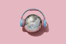 Disco Ball And Headphones On Pink Backgournd. Concept For Party And Celebration