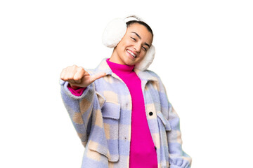 Poster - Young woman wearing winter muffs over isolated chroma key background giving a thumbs up gesture