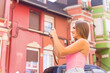 © unai - Blonde tourist in a neighborhood with a street with houses with colorful pink facades, taking a photo