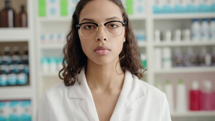 Sticker - Young african american woman pharmacist standing with serious expression at pharmacy