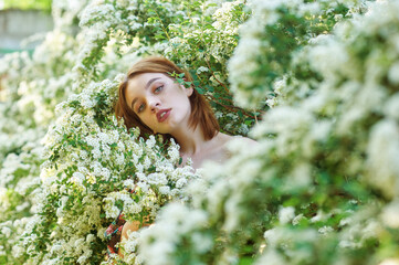 Young beautiful girl on a summer day among flowering trees