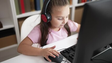 Poster - Adorable hispanic girl student using computer and headphones sitting on table at classroom