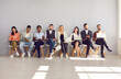 © Studio Romantic - Group of different multiethnic people sitting in row in waiting room before interview or meeting. People read resumes, view documents and use digital devices while sitting in empty lobby with sunlight