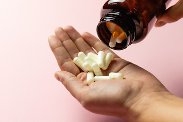 Zinc tablets in the hand on a pink background.