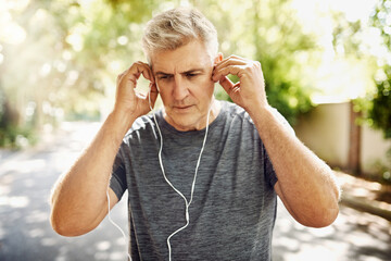 Sticker - Fit, mature and healthy or sporty athlete resting after morning run, listening to music outdoors with earphones. Male jogger about to exercise or do cardio training workout for wellness lifestyle.