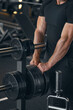 © USM Photography - Muscular strong arms of bodybuilder. Barbells plates. Muscular man trains strong arms. Camera focus on the hands. Barbell workout