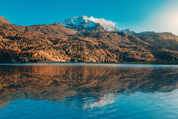 Fotobehang - Amazing nature scenery. Stunning alpine Landscape. View on forest on the hill and majestic rocky mountain range with reflection on Champfer lake. Silvaplana. Switzerland, Europe. natural background