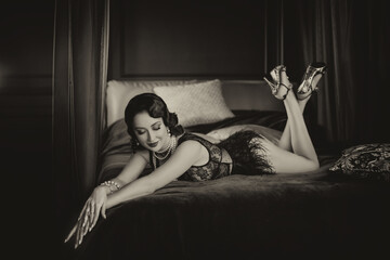 sexy happy woman lies on vintage bed, underwear dress ostrich feather. girl fashion model smiling beauty face. luxury interior room. Black and white sepia color image old style photo retro lady 1920s 