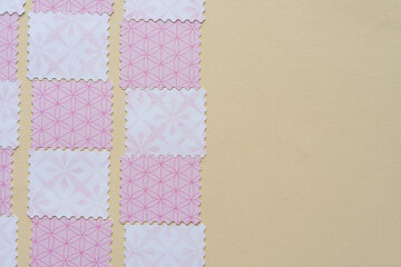 Wall Mural - pink paper tiles with stamp-like detailing on dark beige paper