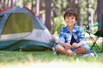 Wall Mural - The best summer vacation ever. Portrait of a young boy sitting in the forest in front of a tent.