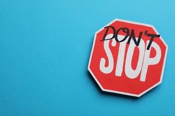 Don't stop - motivational phrase. Road sign sticker with added written text on light blue background, top view