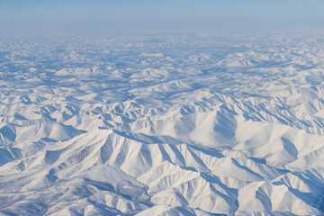 Wall Mural - aerial view of snow-capped mountains and river. winter snowy mountain landscape. air travel to the f