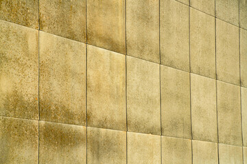 Row of cement square grids with vertival and horizontal grout lines on the side of building on the exterior of cement structure