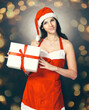 © yurolaitsalbert - pretty young woman dressed as Santa Claus holds Christmas gift. Beautiful bokeh effect from a garland.