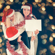 © yurolaitsalbert - three young girls in costume of Santa Claus showing blank sheets. Beautiful bokeh effect from a garland.