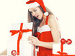 © yurolaitsalbert - beautiful young woman in a Christmas costume looking at a box of Christmas gifts.