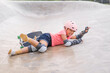 © kornnphoto - asian child or kid girl ride skateboard or surf skate and slipping fall to fail on wave bank ramp by surfing in skatepark for extreme sports to wear helmet protect wrist knee support for body safety