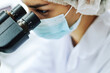 Macro shot of female scientist looking in microscope while working on medical research, with copy space