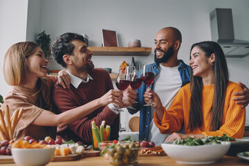 Wall Mural - Happy young people toasting with wine while having dinner at home together