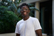 © CarlosBarquero - Portrait of black man very happy, smiling and looking at camera. An African American student sincerely smiles while standing outdoors. The guy is wearing a white t-shirt