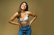 © AntonioDiaz - Excited fit woman wearing a bra and jeans smiling against a studio background