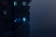© badahos - Residential building during a blackout at night in the fog. After the russian missile attacks. Kyiv, Ukraine.