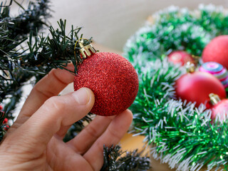 Close-up of red ball in hand on Christmas tree