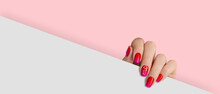 Manicured Womans Hand Holding White Paper. Fashionable Red And Pink Color With Flower Art Nail Design