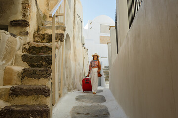 Wall Mural - Young woman with  walks through the old streets in Greece