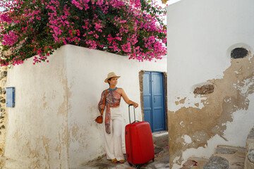 Wall Mural - Young woman with a red suitcase in island  Santorini