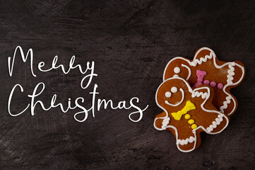 Wall Mural - Two gingerbread men with colorful icing placed in the lower corner of the image on a black metallic background with label 