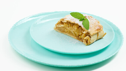 Canvas Print - Slice of apple strudel on a round plate, white background