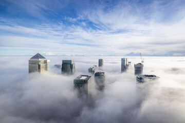 Wall Mural - The modern skyline of Canary Wharf, London, during a foggy day with the tops of the skyscrapers looking out of the clouds