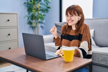 Sticker - Young beautiful woman using computer laptop doing video call screaming proud, celebrating victory and success very excited with raised arm