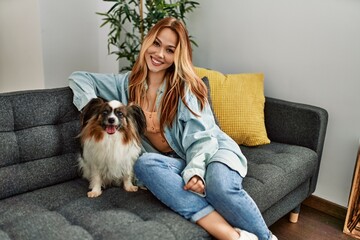 Sticker - Young caucasian woman smiling confident sitting on sofa with dog at home