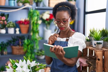 Sticker - African american woman florist reading notebook with doubt expression at florist store