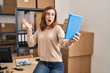 Canvas Print - Young woman working ecommerce doing video with tablet scared and amazed with open mouth for surprise, disbelief face