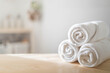 White rolled towels on wooden countertop spa beauty body care hygiene procedure at bathroom. Blurred background