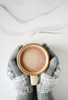 Gloves holding mug of hot chocolate