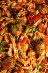 Wall Mural - Texture of pasta in tomato sauce with meatballs as a background. A close shot of pasta with tomato sauce. Macro photo. Tagliatelle pasta with tomato sauce and meatballs.