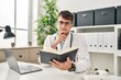 © Krakenimages.com - Young hispanic man doctor using laptop reading book at clinic