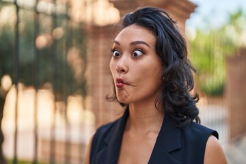 Wall Mural - Young beautiful hispanic woman smiling confident doing funny gesture with lips at street