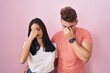 © Krakenimages.com - Young hispanic couple standing over pink background tired rubbing nose and eyes feeling fatigue and headache. stress and frustration concept.